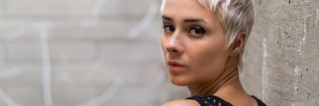 photo of a woman with short hair looking over her shoulder into camera
