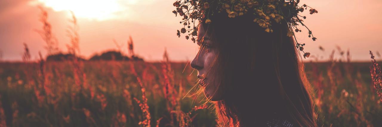 The Pagan 'Wheel of the Year' Helps When the Holidays Trigger My PTSD photo of a woman at sunset in a field wearing a flower headdress