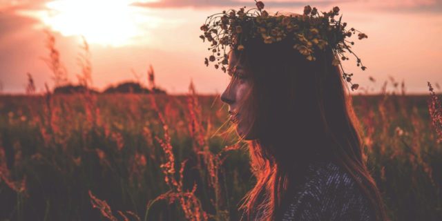 When the Holidays Are Triggering, the Pagan ‘Wheel of the Year’ Helps My Trauma Recovery photo of a woman at sunset in a field wearing a flower headdress