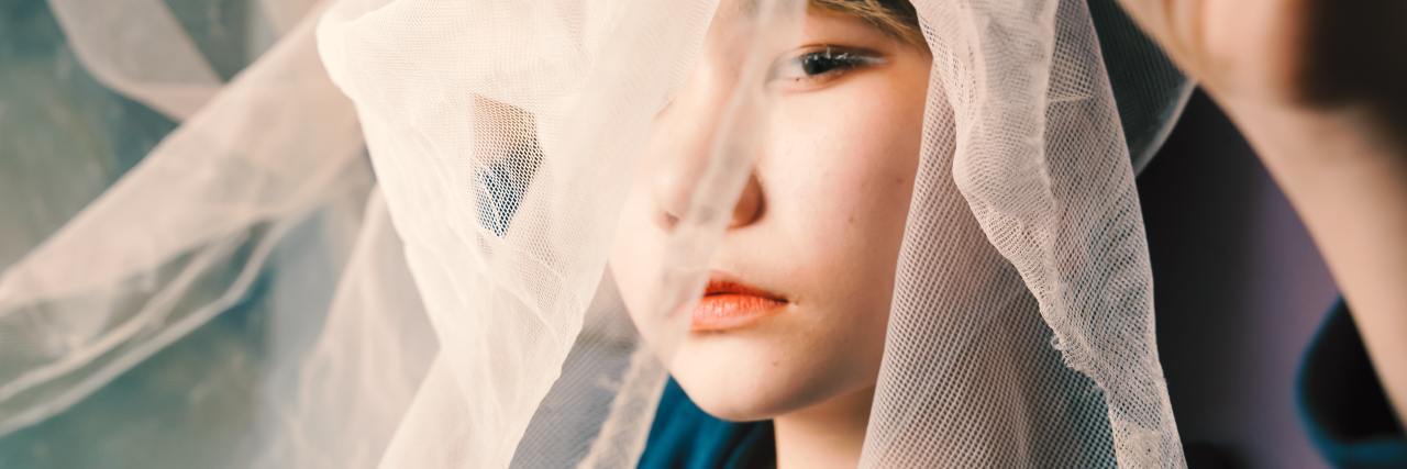 I've Actually Found the Silver Lining to My Trauma photo of a young woman partially covering her face with white lace