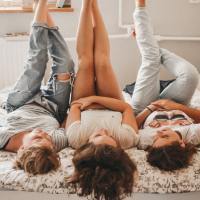 photo of three friends lying down together with legs upright, smiling and chatting