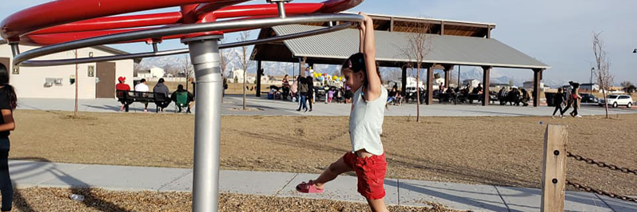 Lexy hanging on a spinning piece of playground equipment.