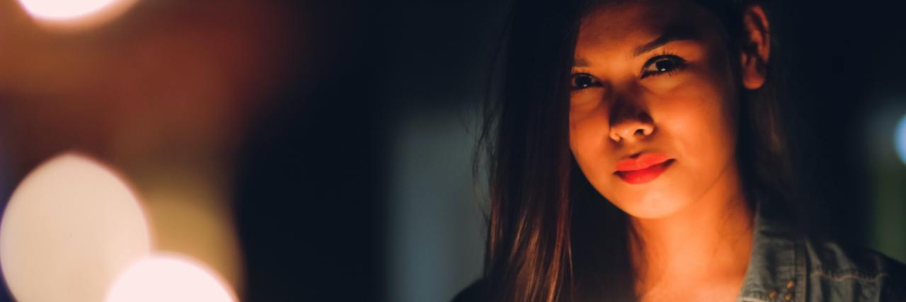 What 'Masking' and 'Mirroring' Mean in ADHD Behaviors photo of a woman holding lights in her hands and up to her face, looking into camera