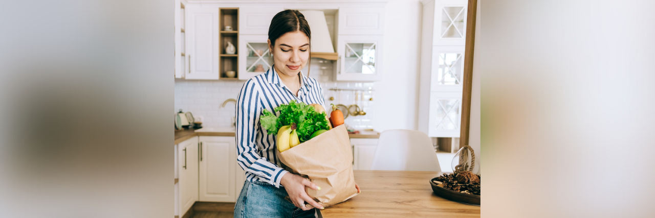 The Importance of Nutrition in Early Addiction Recovery Woman holding brown bag full of fresh vegetables in kitchen
