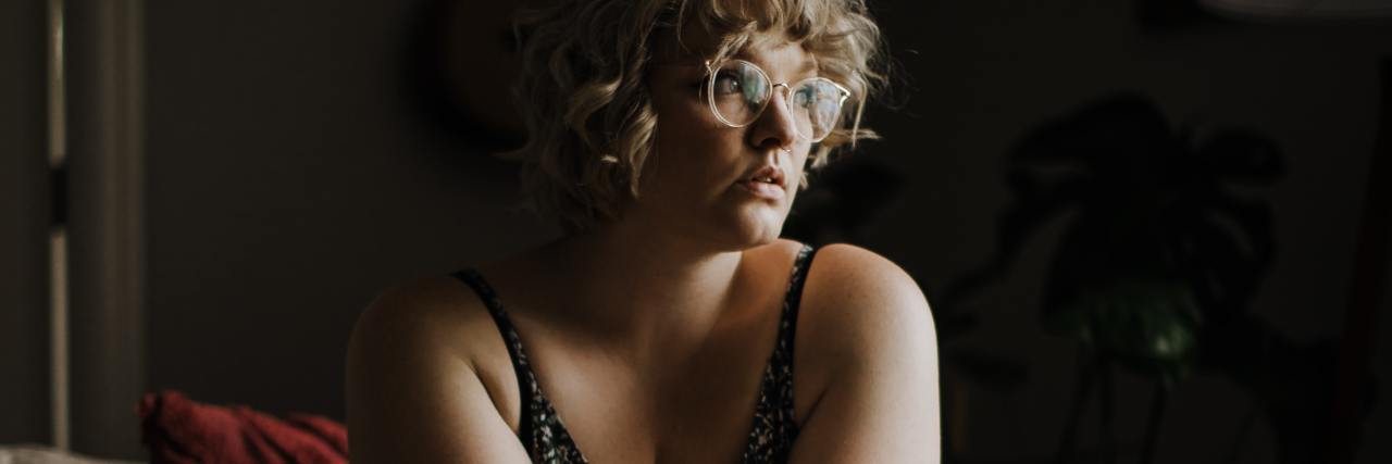 How the ‘It's Bigger Than Me’ Campaign Is Harming Fat People for Profit photo of a woman sitting on a couch in near darkness looking serious