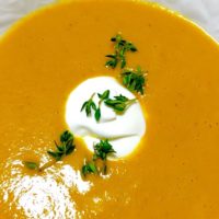 IBS-Friendly Butternut Squash Soup with a garnish on top sitting on a plate.