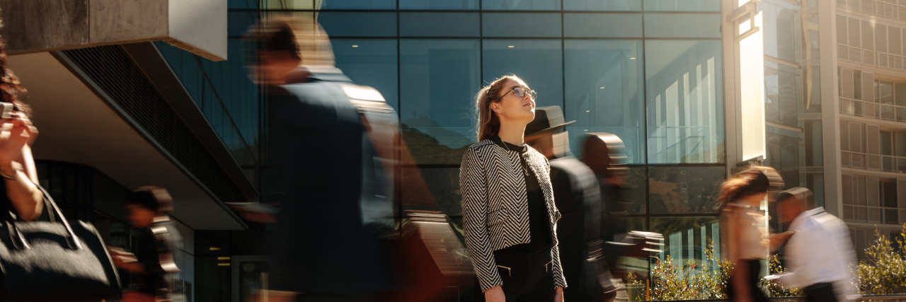 The Truth About Seeming 'High-Functioning' as a Neurodivergent Person Woman standing alone in a crowded city.