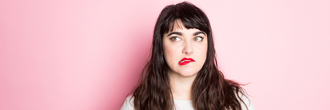 Portrait of a Woman with tattoos and red lipstick against a pink background