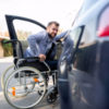 Disabled man attempting to get in the car.