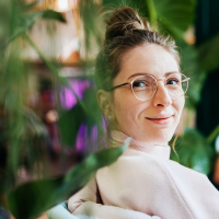 Portrait of a woman sitting by green plants and slightly smiling