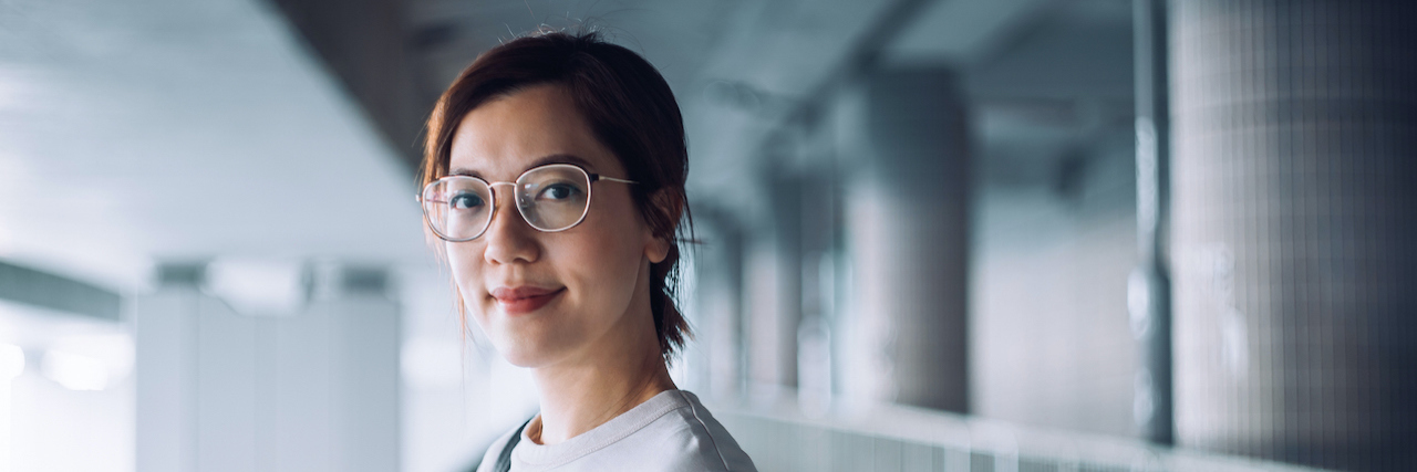 Perpetuating Stigma When You Assume My Scar Is From Self-Harm Portrait of confident Asian woman looking at camera with smile, standing against urban bridge in the city