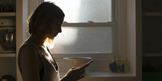 Silhouette of young woman holding her phone