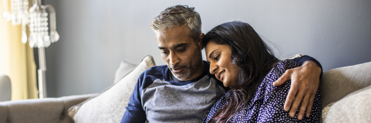 When Chronic Illness Means Intimacy Looks Different Than It Does on TV Husband and wife embracing on couch.