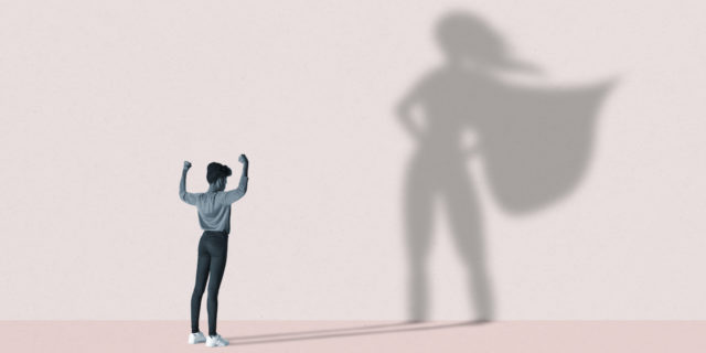 Illustration of woman flexing muscles in front of large superhero shadow on pink background