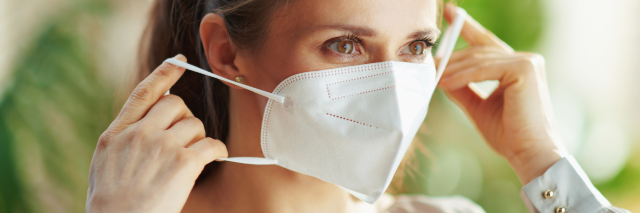 How COVID Vaccine Refusers Make My Life With Disabilities Harder Woman putting on COVID mask.