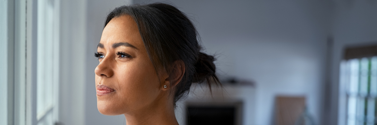 Innovative Tools to Support Your Mental Wellness: Neurofeedback and Biofeedback Black woman looking outside the window with a pensive expression