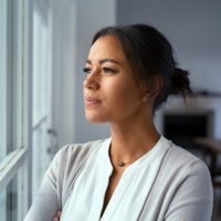 Woman looking outside the window with a pensive expression