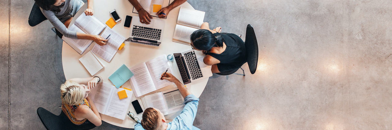 The Consequences of Hiding My Schizophrenia in Graduate School Top view of group of students sitting together at table.