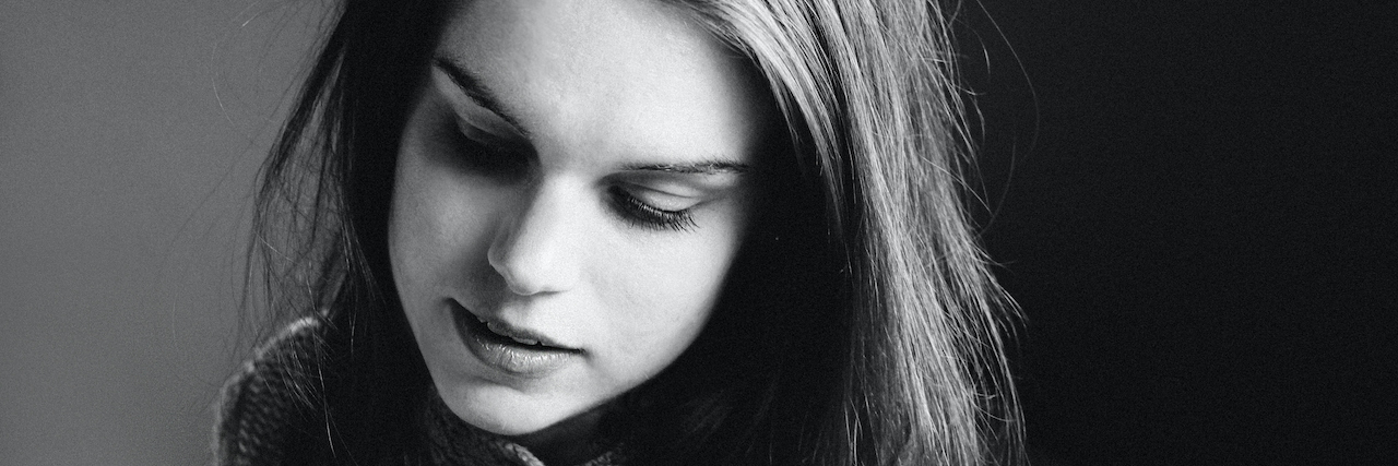 The Turning Point in My Eating Disorder Recovery A black and white photo of a woman with her eyes closed. She has dark hair and is wearing a sweater