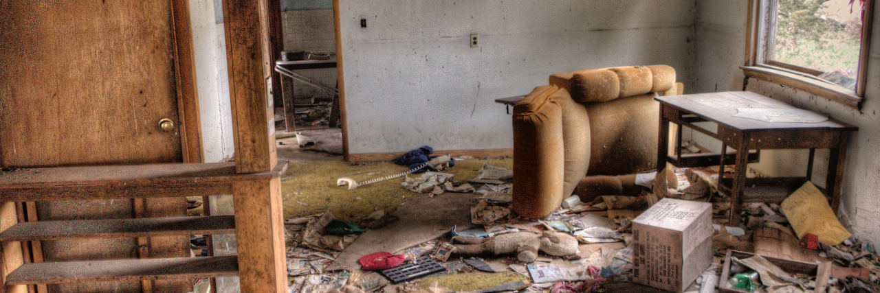 Inside of a house that's destroyed -- trash on the floor, broken chairs and windows