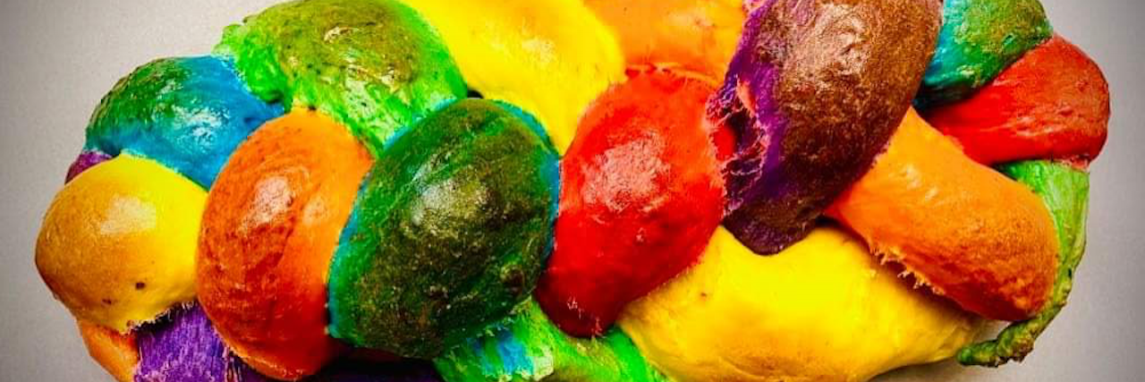 What Hanukkah Is Like With Hypermobile Ehlers-Danlos Syndrome image of loaf of brightly colored bread, each strand braided together into one. Features colors of the rainbow.
