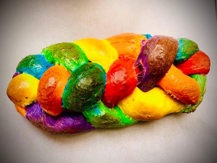 image of loaf of brightly colored bread, each strand braided together into one. Features colors of the rainbow.