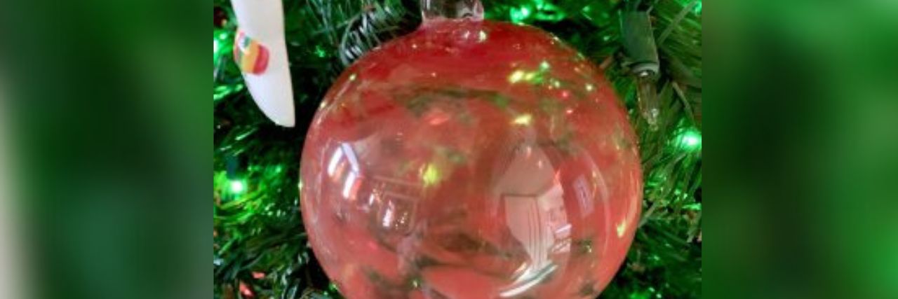Red and orange glass blown ornament hanging on a Christmas tree