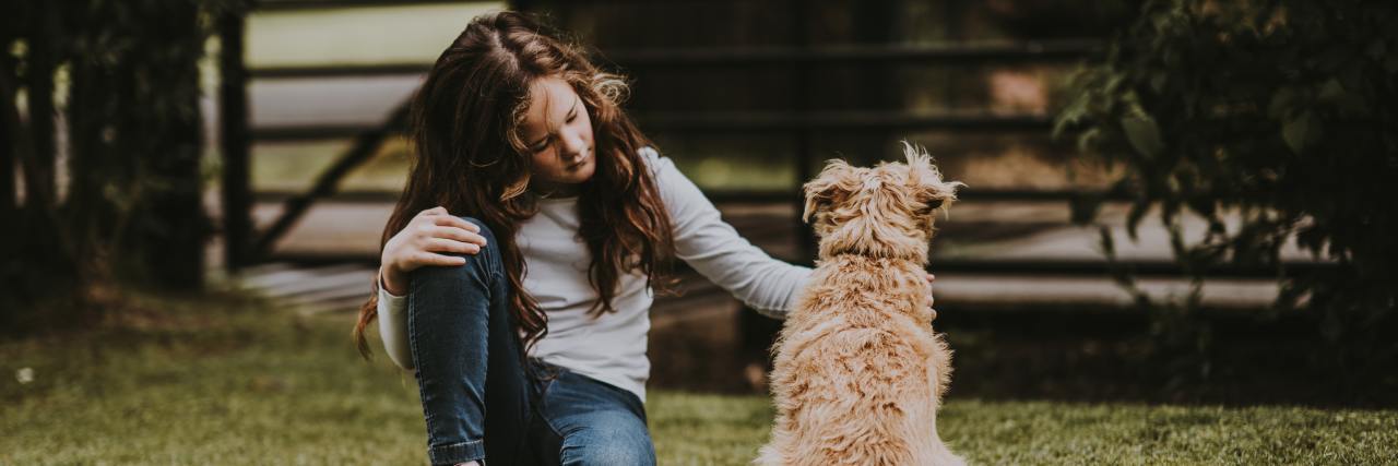 Why the ACEs Questionnaire Doesn't Accurately Reflect How Trauma Can Impact Someone photo of a young girl sitting on the ground with a dog