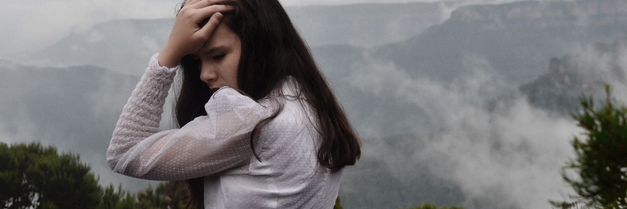 photo of a young woman looking worried with mountains in the background