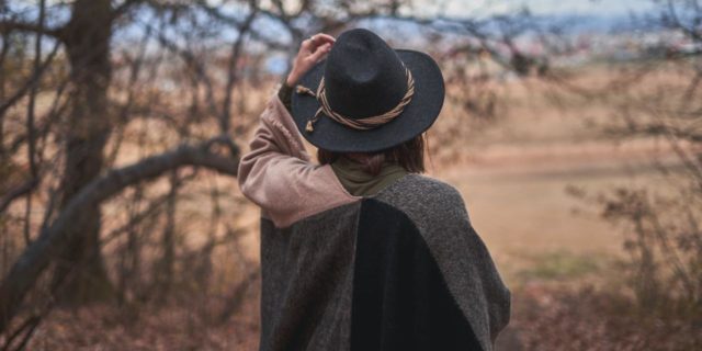 Back of a woman with a sweater and hat, walking outside during the fall