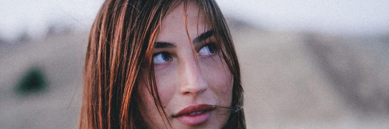 Woman outside with blurred background, looking up and away from camera