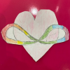 A cut-out drawing of a pink heart hugged by the neurodivergent symbol (an infinity sign with rainbow colors). The image rests on a pink background.