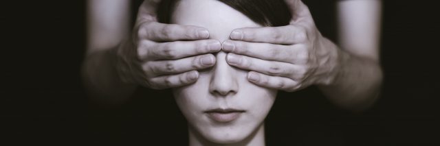 photo of a woman whose eyes are covered by an older person's hands from behind