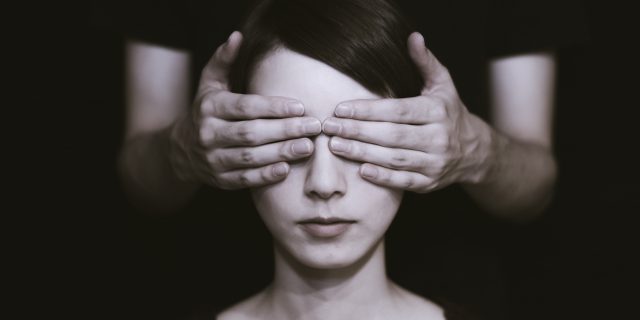 photo of a woman whose eyes are covered by an older person's hands from behind