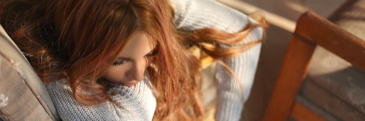 I Used to Hate When People Said 'At Least You Have Your Physical Health' A woman with red hair laying over a chair