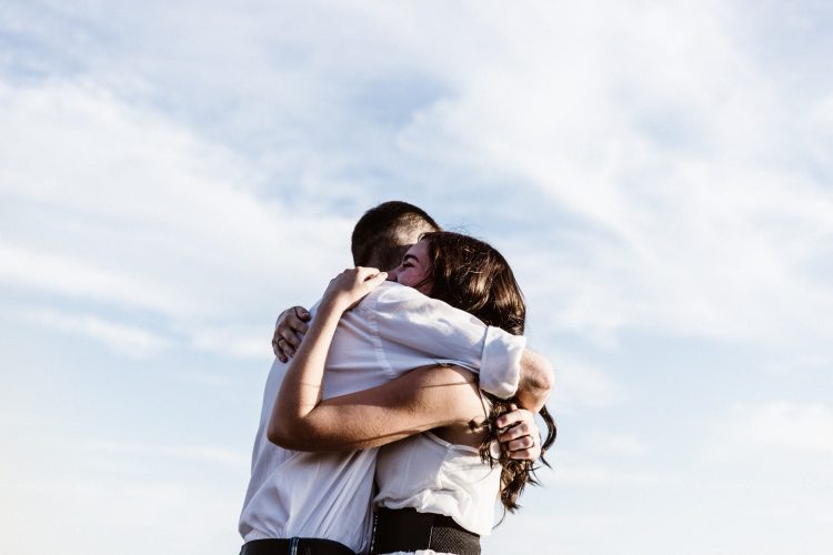 Man and woman embracing with blue sky in background