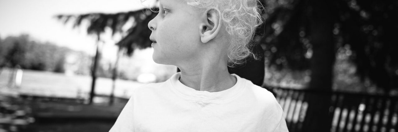 Staying in the Present as a Parent of a Child With Rare Disease The author's son at 5 years old. He has curly blonde hair and is wearing a white T-shirt while looking to the side.