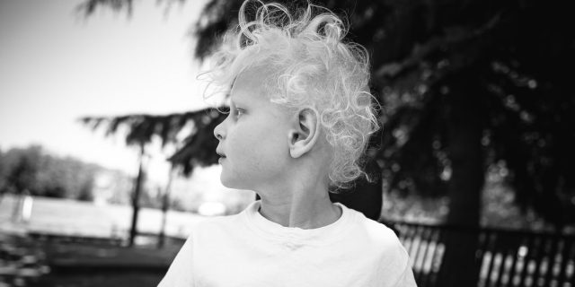 The author's son at 5 years old. He has curly blonde hair and is wearing a white T-shirt while looking to the side.