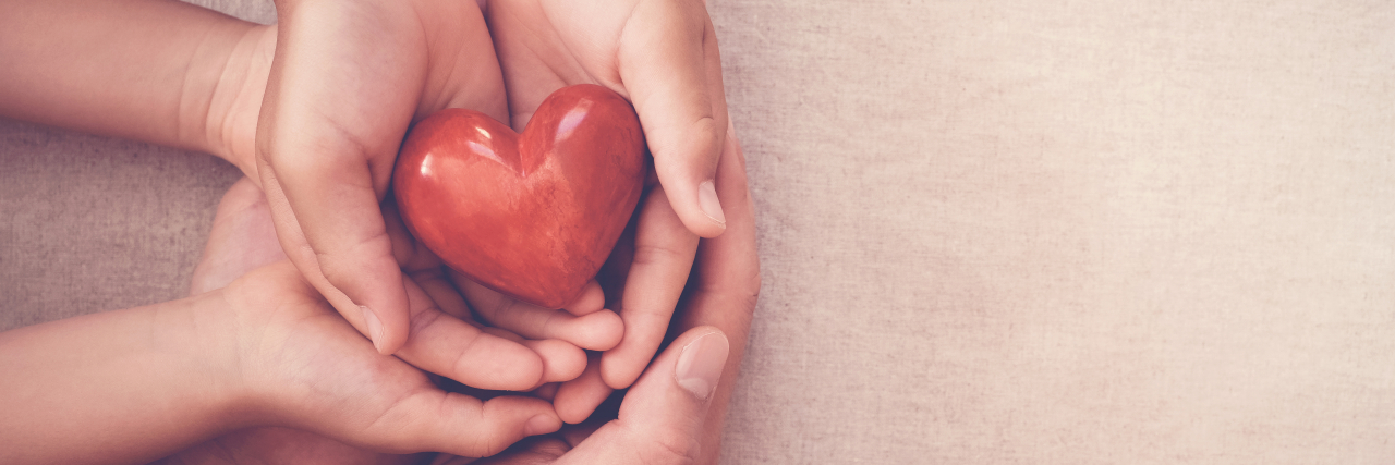 How People With Chronic Illness Can Support Our Caregivers hands holding red heart.