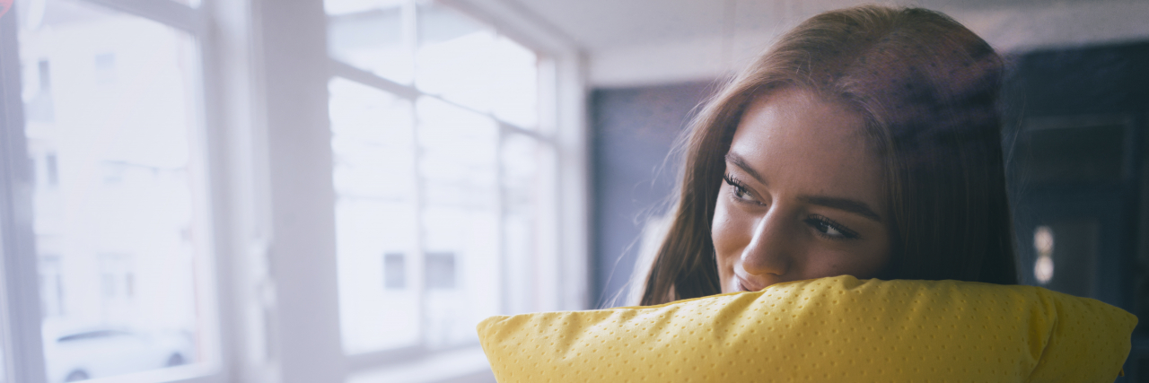 Woman holding yellow pillow.