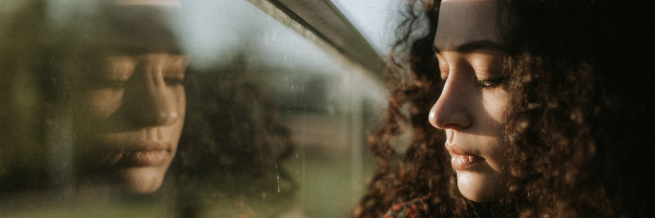 How Burnout Impacts My Autism Sad woman near window.