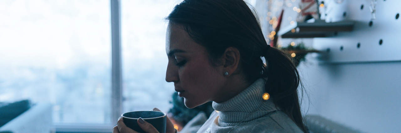 Managing Anxiety During the Build-Up to the Holidays Photo of a woman drinking hot chocolate in the living room of her apartment; enjoying the peaceful winter morning.