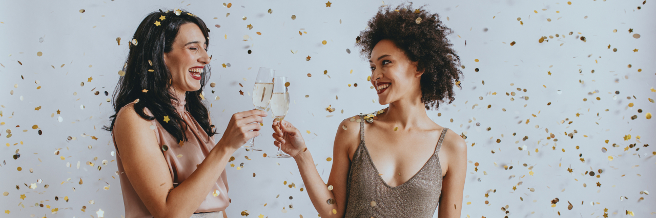 Read This If You Don’t Feel Like You’ve Accomplished Anything in 2021 Two women dressed up clinking glasses of champagne, smiling