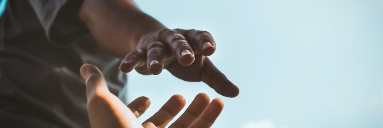 Helping Others at Your Own Expense With BPD Hands reaching out to help each other with blue sky in background