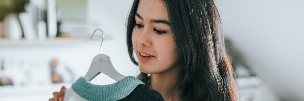 Navigating the Transition From Chronic Illness to Full-Time Work Woman choosing a sweater from her closet.