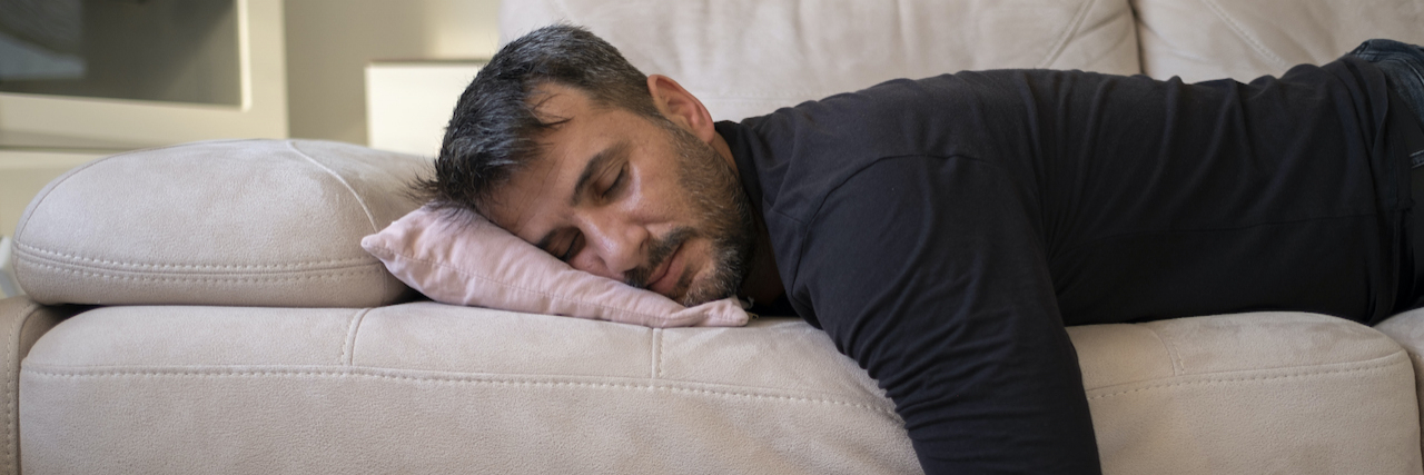 Man laying on sofa with eyes closed