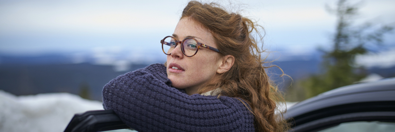 How to Find Meaning and Purpose Beyond Work With Mental Illness Woman leaning on her car door overlooking landscape while having a break from driving