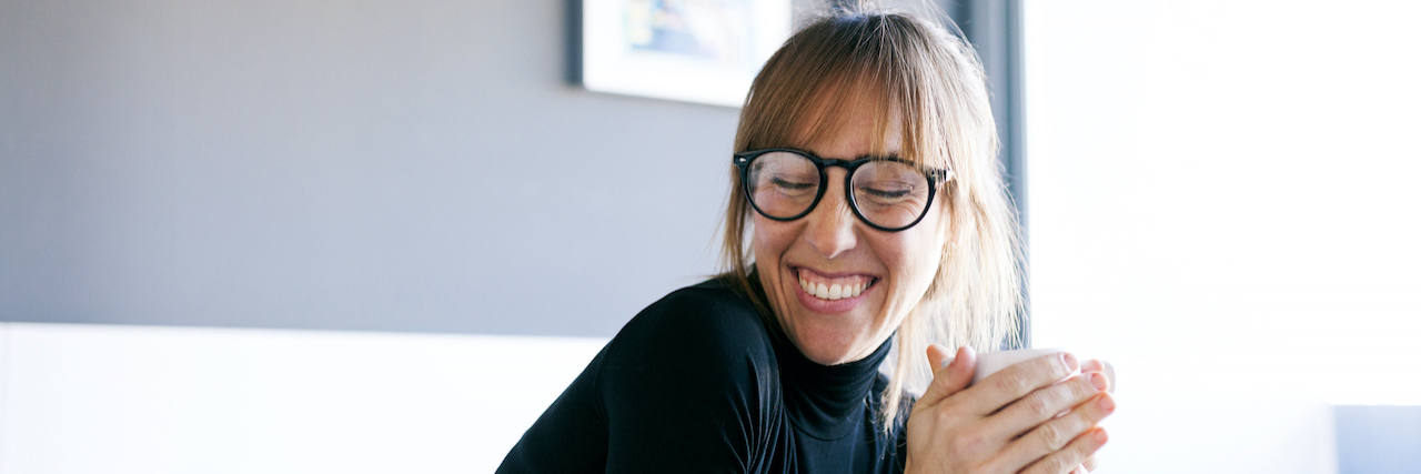 Accepting My Excessive Talking With ADHD Is a Part of Me Smiling young woman at home drinking cup of coffee