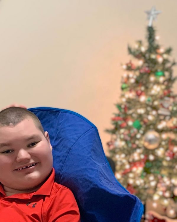 Jacob sitting up in front of Christmas tree