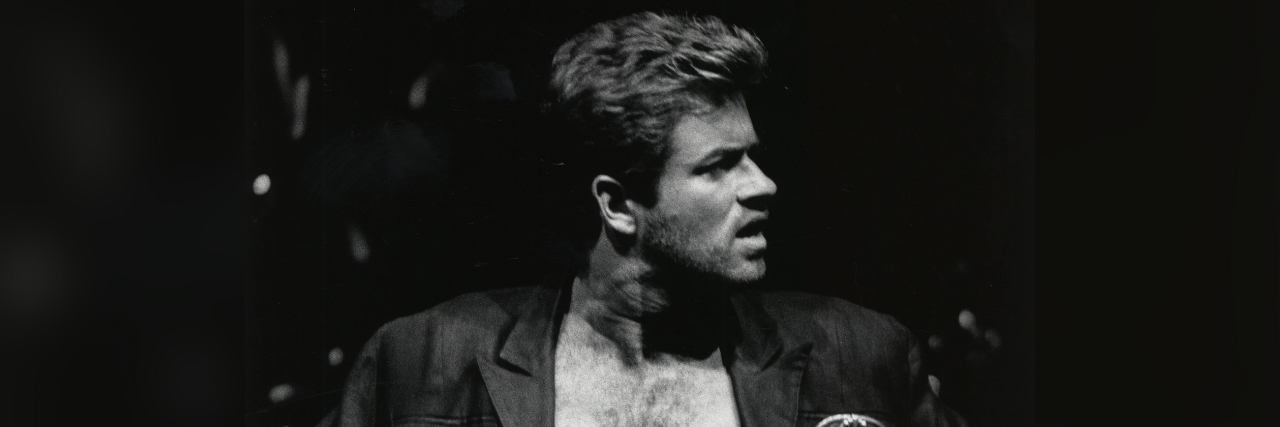 Musician George Michael with his shirt unbuttoned looking away